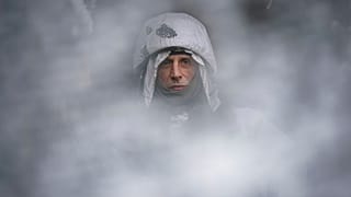 Un soldat ukrainien photographié à travers une maille de camouflage sur la ligne de front dans la région de Louhansk, dans l'est de l'Ukraine, samedi 29 janvier 2022. 