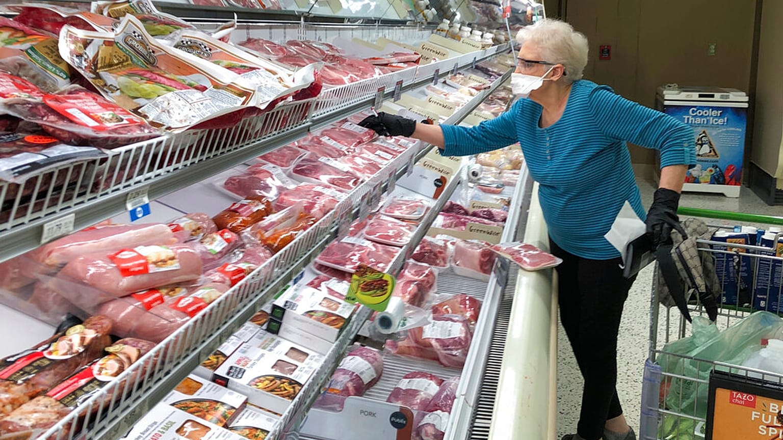 Un'anziana al banco salumi in un supermercato