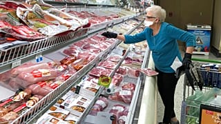 Un'anziana al banco salumi in un supermercato