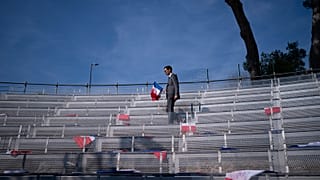 A campaign worker places French flags on seats, prior to a National Rally event in Frejus