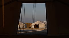 A migrant sits inside a tent at the new temporary refugee camp at Karatepe, near Mytilene town, on the northeastern island of Lesbos