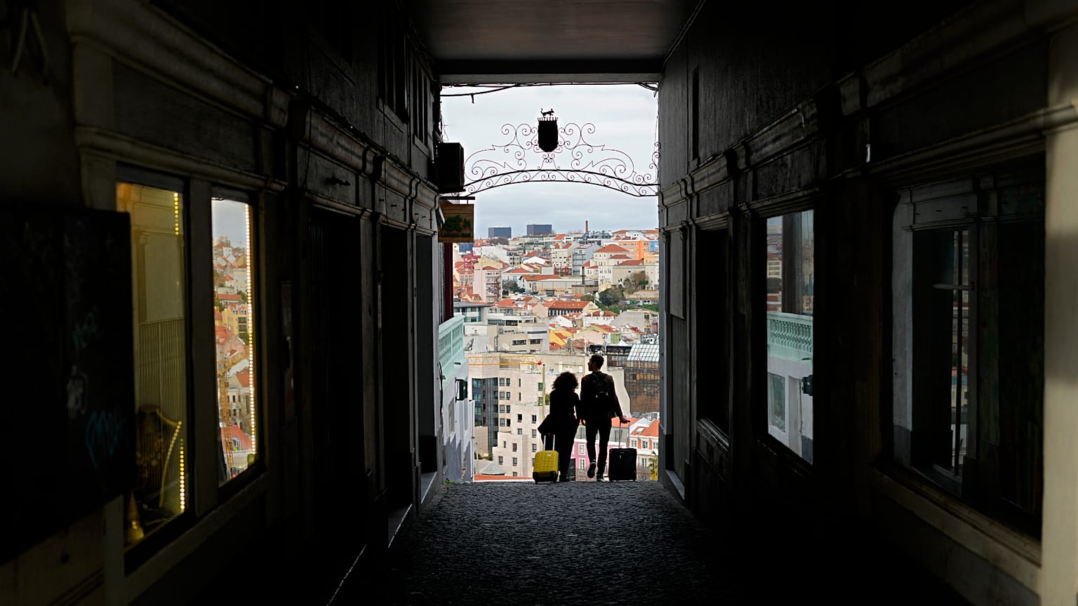 Um casal transporta malas de viagem em Lisboa