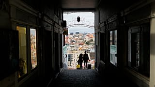 Um casal transporta malas de viagem em Lisboa