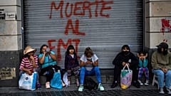 Des manifestants assis devant un graffiti où l'on peut lire en espagnol "Mort au FMI" après une manifestation à Buenos Aires (Argentine), mardi 8 février 2022. 