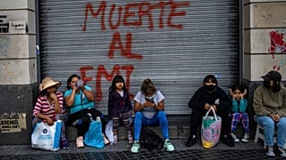 Des manifestants assis devant un graffiti où l'on peut lire en espagnol "Mort au FMI" après une manifestation à Buenos Aires (Argentine), mardi 8 février 2022. 