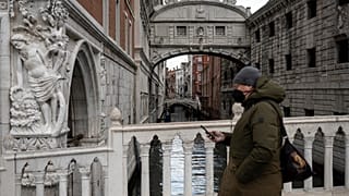 Homem com máscara passeia em Veneza, Itália