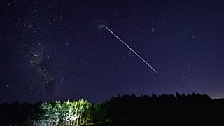 FILE- In this file photo taken on February 06, 2021, this time-exposure image shows a trail of a group of SpaceX's Starlink satellites passing over Uruguay