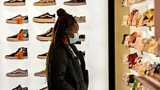 A woman wears a protective mask as she looks at shoes in Rue Neuve in Brussels, Belgium, Saturday, Nov. 27, 2021.