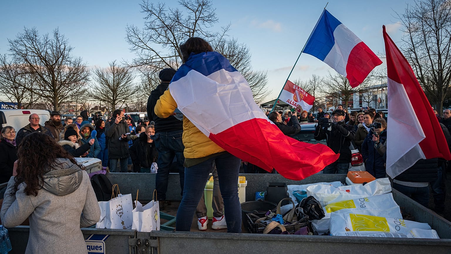 Participants of the so-called "Freedom Convoy" wave French flags as they gather before leaving Strasbourg for Paris on Friday.