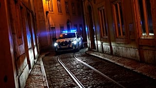 A police car drives through a narrow street of the old Alfama neighbourhood in Lisbon.