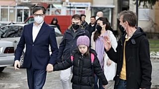 The President of the Republic of North Macedonia, Stevo Pendarovski, holds the hand of Embla Ademi as he walks her to school on February 7, 2022.