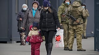 A woman holds a child's hand as they cross from Ukrainian government to pro-Russian separatists controlled territory in Stanytsia Luhanska.
