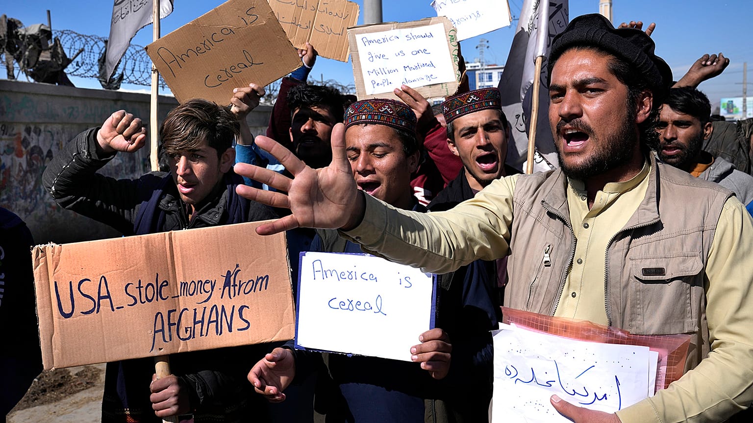 Afghan protesters hold placards and shout slogans during a protest condemning President Joe Biden's decision, in Kabul