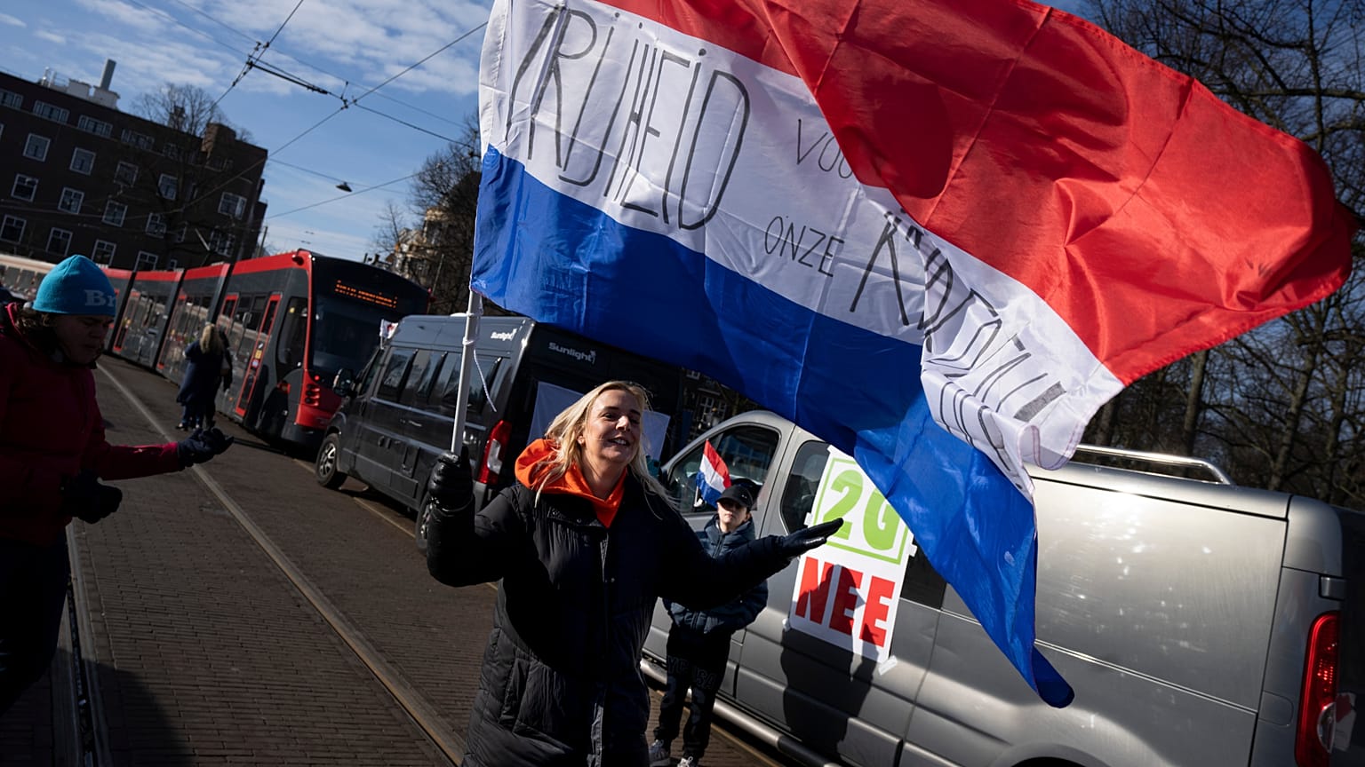 Una mujer con una bandera neerlandesa en la que se lee "libertad para nuestros hijos" en la entrada de la sede del Gobierno en La Haya, Países Bajos, el 12 de febrero de 2022.