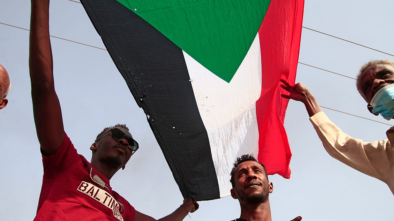 رجال يرفعون العلم السوداني ويهتفون بشعارات خلال مظاهرة تطالب بالحكم المدني وتندد بالإدارة العسكرية في جنوب العاصمة الخرطوم في 10 فبراير 2022.