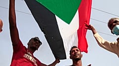 رجال يرفعون العلم السوداني ويهتفون بشعارات خلال مظاهرة تطالب بالحكم المدني وتندد بالإدارة العسكرية في جنوب العاصمة الخرطوم في 10 فبراير 2022.
