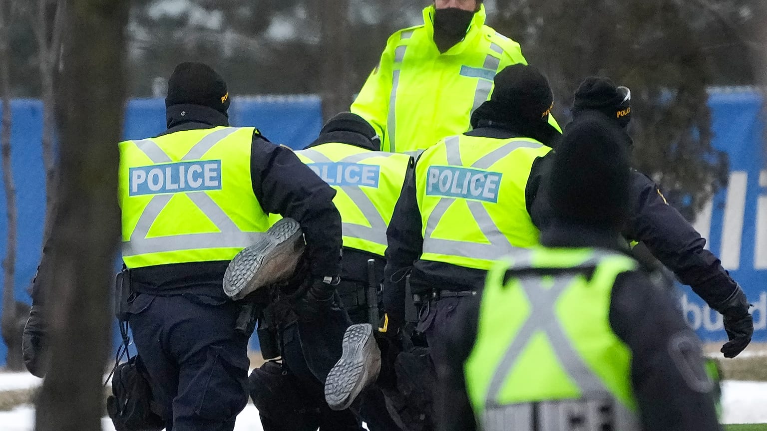 Police arrest a person as they walk the line to remove truckers and supporters protesting against COVID-19 restrictions in Windsor, Ontario, Canada, Feb. 13, 2022. 