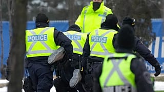 Police arrest a person as they walk the line to remove truckers and supporters protesting against COVID-19 restrictions in Windsor, Ontario, Canada, Feb. 13, 2022. 