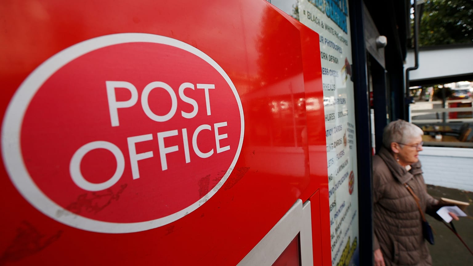 A woman walks out of a Post Office in London, Thursday, Oct. 10, 2013. 