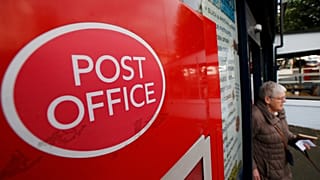 A woman walks out of a Post Office in London, Thursday, Oct. 10, 2013. 