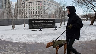A person walks with their dog in front of the U.S. Embassy in Kyiv, Ukraine, Saturday, Feb. 12, 2022.