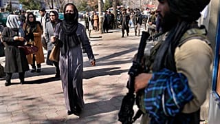 امرأة تمر بجانب مسلح من طالبان في كابول، 13 فبراير 2022