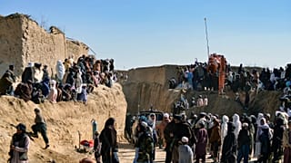 Afghan people gather as rescuers try to reach and rescue a boy trapped down a well in the Afghan village of Shokak, on February 17, 2022.