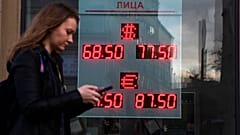 A woman walks past an currency exchange office screen displaying the exchange rates of U.S. Dollar and Euro to Russian Rubles, in Moscow.