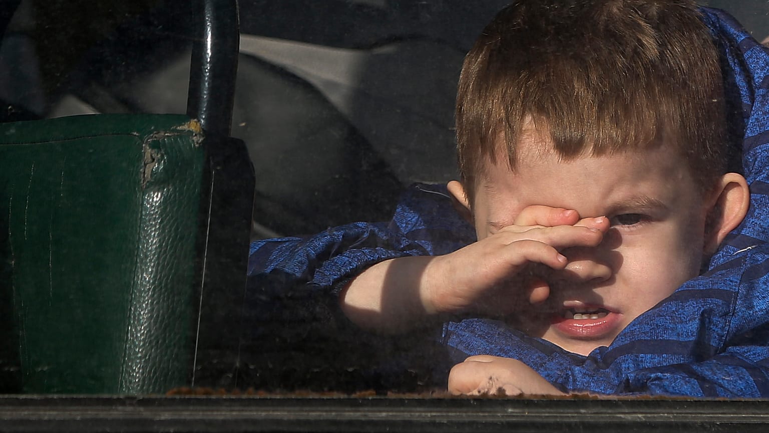 A boy waiting to be evacuated to Russia looks through the window of a bus, in Donetsk, the territory controlled by pro-Russian militants, eastern Ukraine, Sat. Feb. 19, 2022.