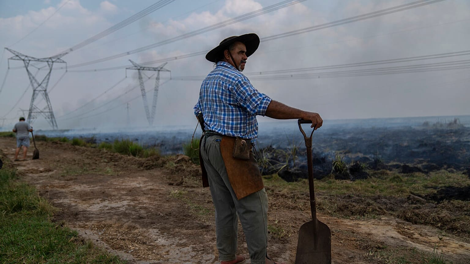 Un agricultor hace una pausa en su trabajo para ayudar a extinguir un incendio cerca de Ituzaingo, provincia de Corrientes, Argentina, el sábado 19 de febrero de 2022.