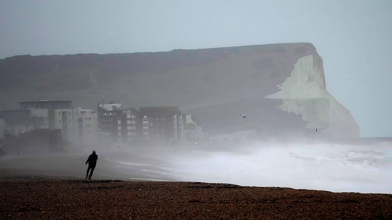 A person walks on Seaford Beach, as Storm Eunice hits Seaford and the south coast of England, Friday, Feb. 18, 2022.