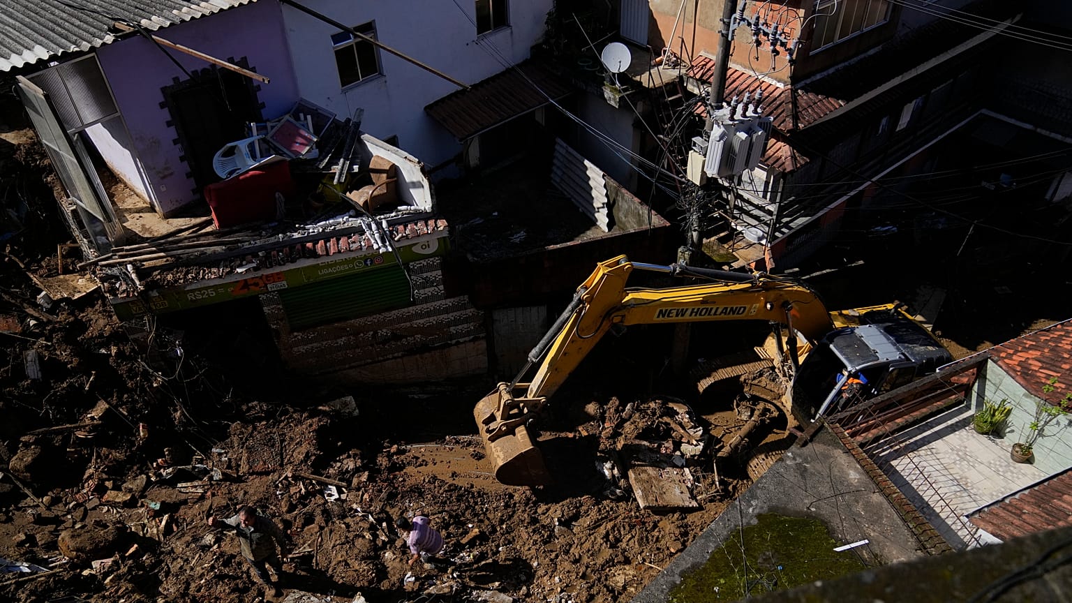 Munkagéppel takarítják el a sarat a házak közül a Rio de Janeiro állambeli Petrópolisban 2022. február 17-én, két nappal a földcs