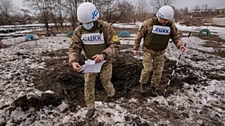 Az orosz-ukrán egyesített ellenőrző és koordináló központ (JCCC) tagjai egy tüzérségi lövedék által okozott krátert vizsgálnak a kelet-ukrajnai Luhanszk megyében 