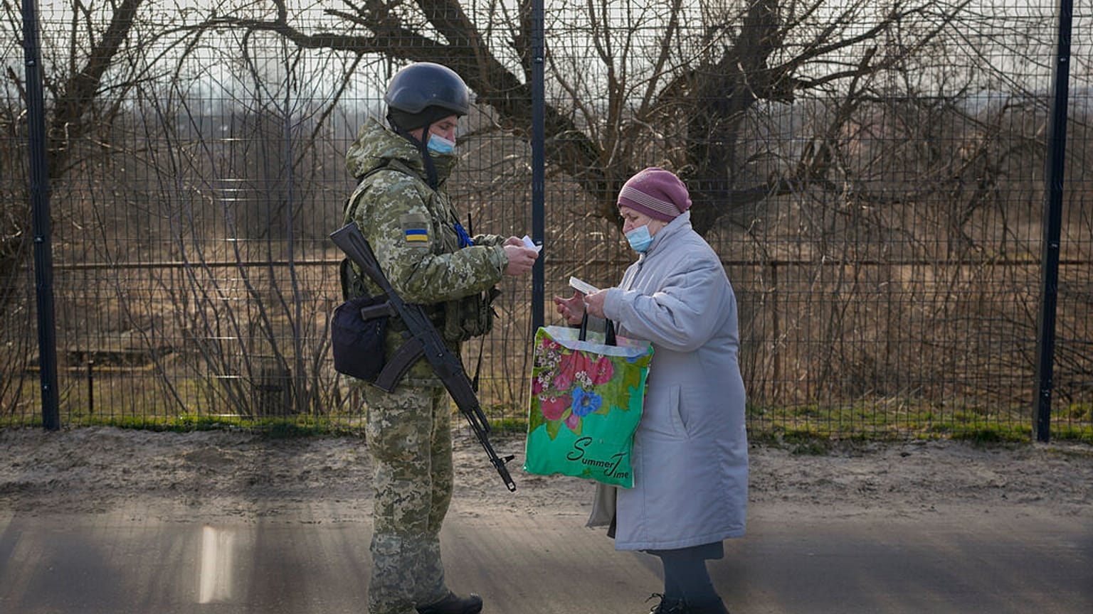 A Ukrainian serviceman checks the documents of a woman crossing to government controlled areas from pro-Russian separatists controlled territory in Stanytsia Luhanska