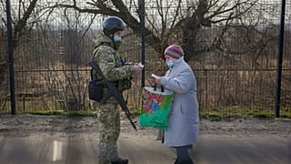 A Ukrainian serviceman checks the documents of a woman crossing to government controlled areas from pro-Russian separatists controlled territory in Stanytsia Luhanska