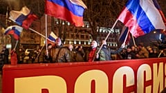 Menschen schwenken russische Nationalflaggen und feiern hinter einem Transparent mit der Aufschrift "Russland" im Zentrum von Donezk, 