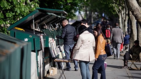 People look at books and posters as they walk past booksellers "bouquinistes", near the river Seine