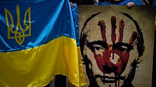 A protestor holds a banner depicting Russian President Vladimir Putin during a demonstration in front of the Russian Embassy in Madrid, Spain, Thursday, Feb. 24, 2022.