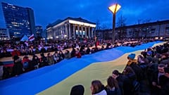 People carry a giant flag of Ukraine to demonstrate against Russian attacks in Ukraine at Independence Square in front of the Parliament Palace in Vilnius, Lithuania