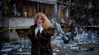 Natali Sevriukova reacts as she stands next to her house following a rocket attack in the city of Kyiv, Ukraine, Feb. 25, 2022.