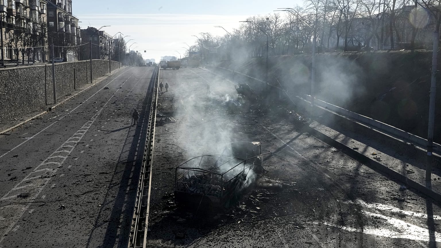 Горящие обломки военных грузовиков на попавшей в субботу под обстрел улице Киева