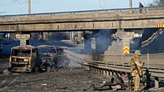 Ukrán katona egy kiégett katonai jármű mellett 