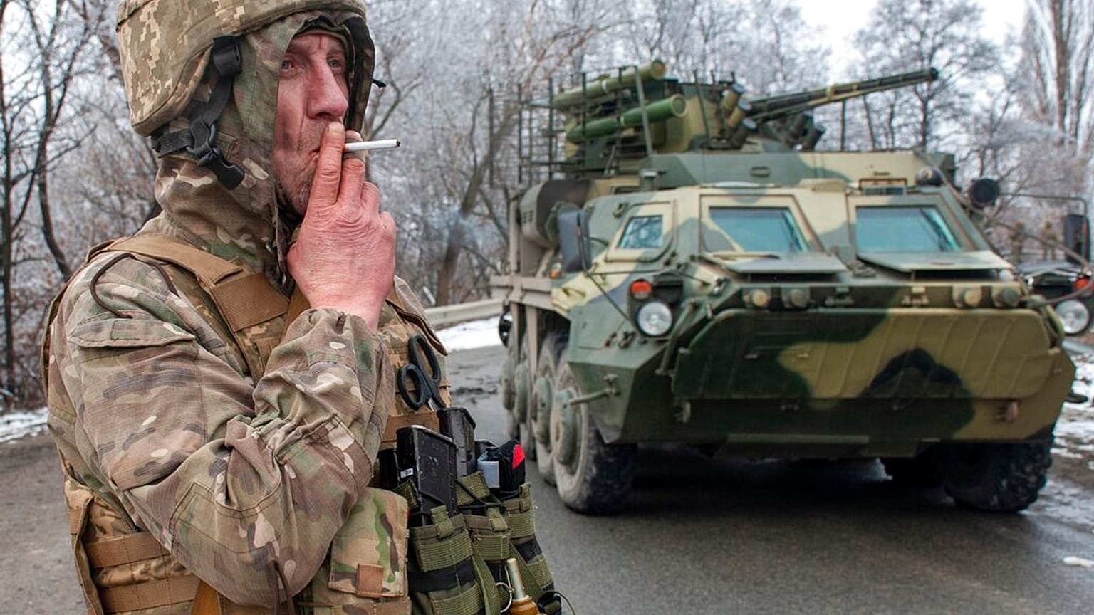 Um soldado ucraniano fuma um cigarro ao pé de um veículo blindado nos arredores de Kharkiv
