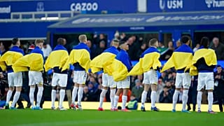 Everton players hold Ukrainian flags before the English Premier League soccer match
