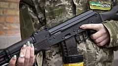 Az ukrán polgári védelem egyik tagja fegyverét tartja járőrözés közben Kijevben