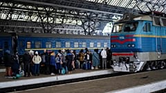 People trying to flee Ukraine stand on a platform as they wait for trains inside Lviv railway station.