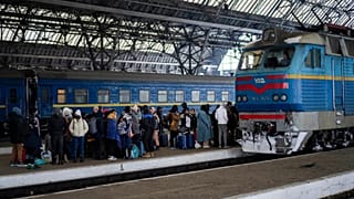 People trying to flee Ukraine stand on a platform as they wait for trains inside Lviv railway station.