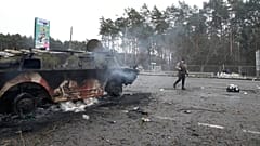 Ein Freiwilliger der ukrainischen Territorialen Verteidigungskräfte geht an einem beschädigten gepanzerten Fahrzeug vorbei, außerhalb von Kiew, Ukraine, 01.03.2022
