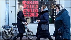أشخاص يمرون عبر شاشة مكتب صرف تعرض أسعار صرف الدولار واليورو مقابل الروبل في موسكو
