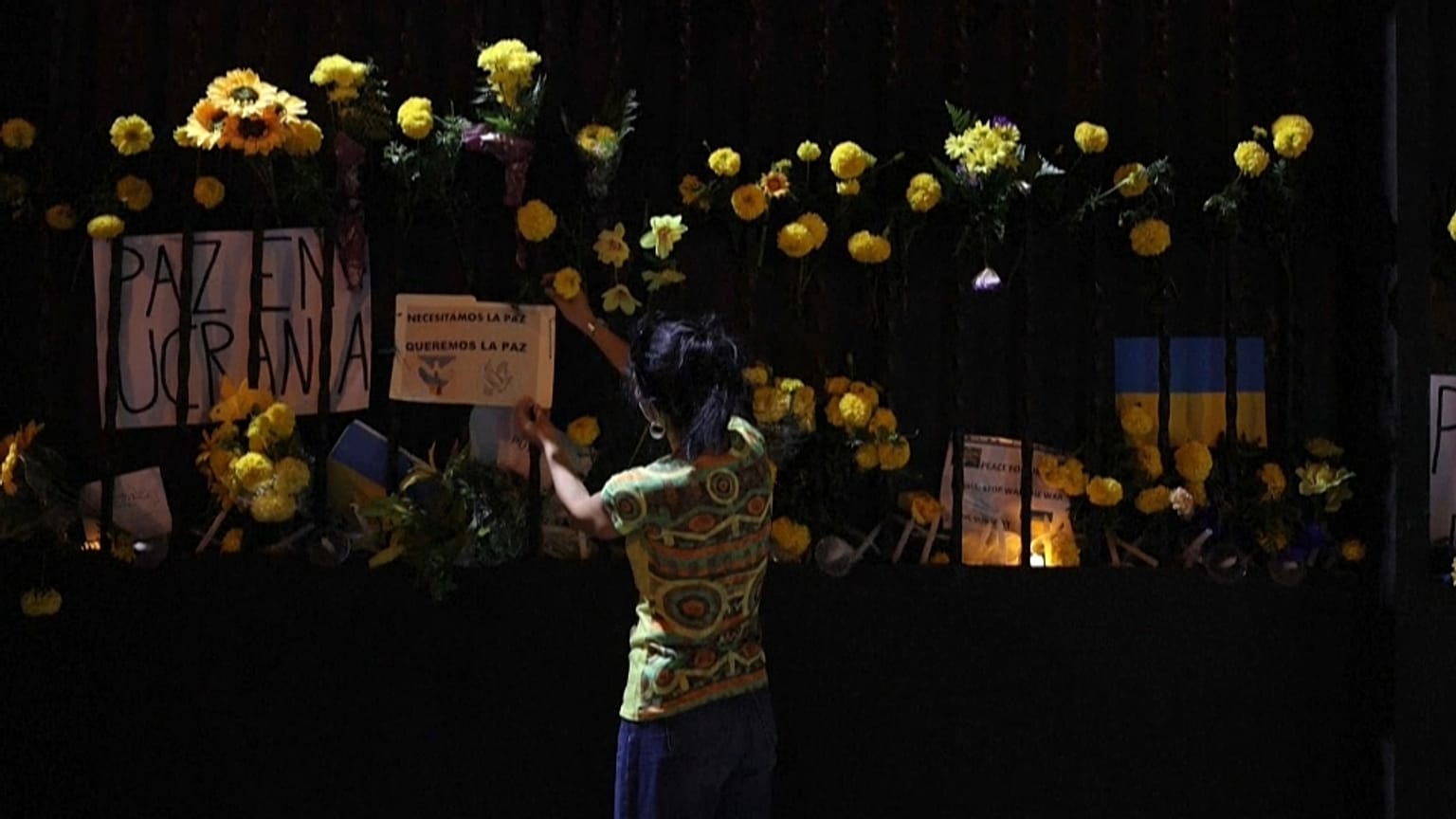 A woman puts a flower at the entrance of the Russian Embassy in Uruguay during a demonstration against the Russian invasion of Ukraine, on March 2, 2022.